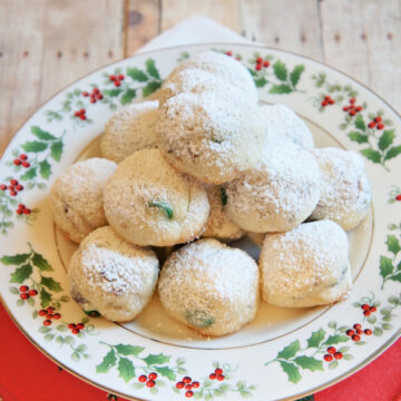 Easy Homemade Christmas Snowball Cookies covered in powdered sugar on a plate
