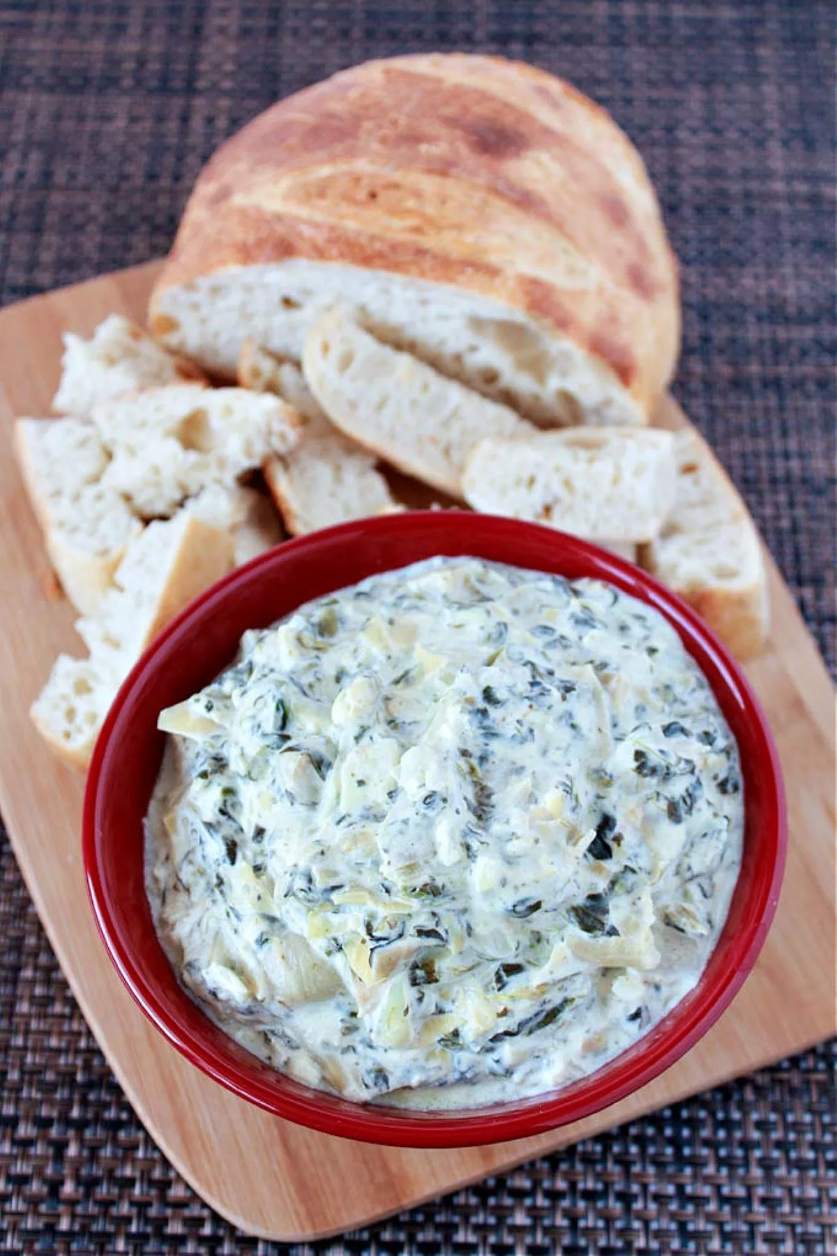 Spinach Artichoke Dip in a red bowl with bread