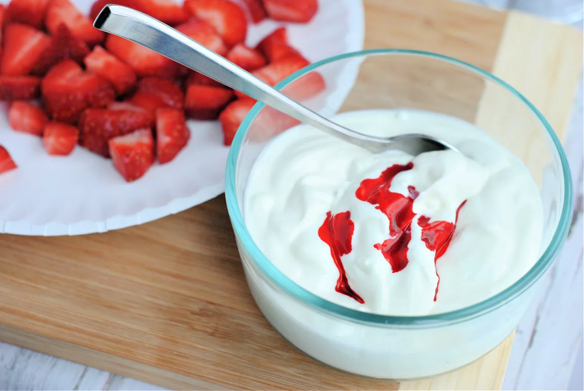 yogurt in a bowl with red food coloring in it and a spoon