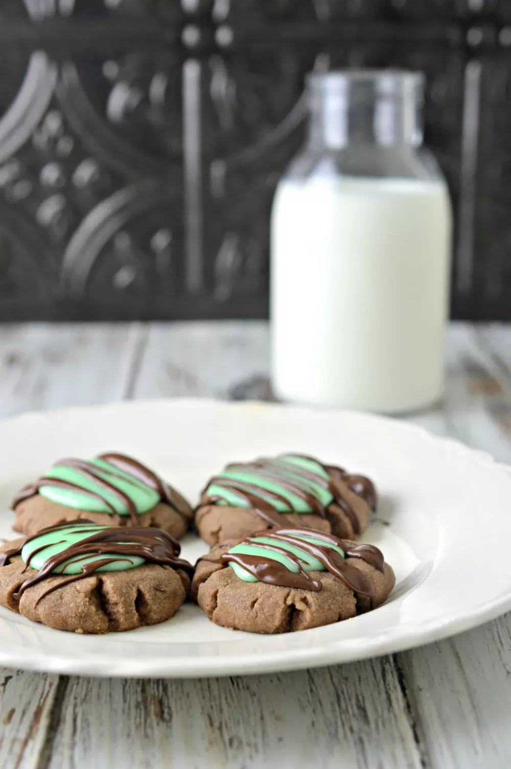 Chocolate cookies with a mint filling and chocolate drizzle with a glass of milk