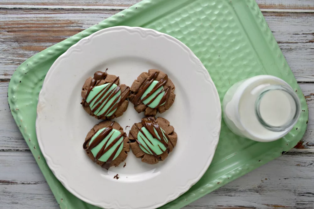 chocolate mint cookies on a green serving late with a glass of milk