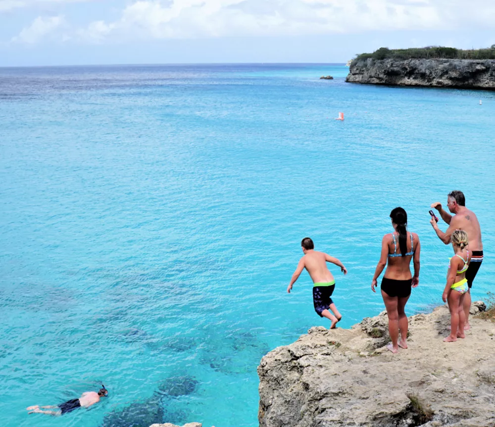 children and families jumping off a cliff to snorkel in curacao at little Knip Beach