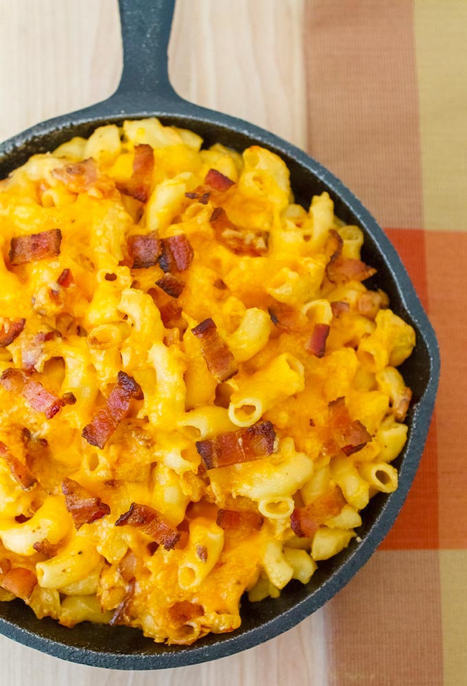overhead shot of cast iron pan filled with  macaroni and cheese and pieces of bacon
