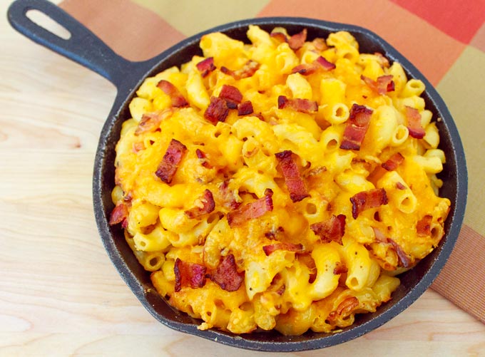 overhead shot of cast iron pan filled with  macaroni and cheese and pieces of bacon