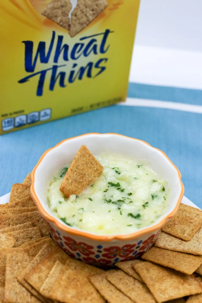 Baked Garlic Brie dip with wheat thins spread out around it