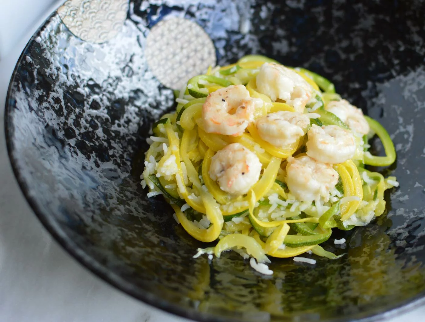 Shrimp and spiralized zucchini on a black plate