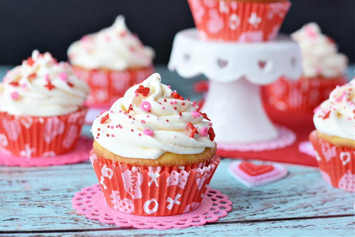 cupcakes with vanilla frosting and sprinkles in valentines day cupcake liners
