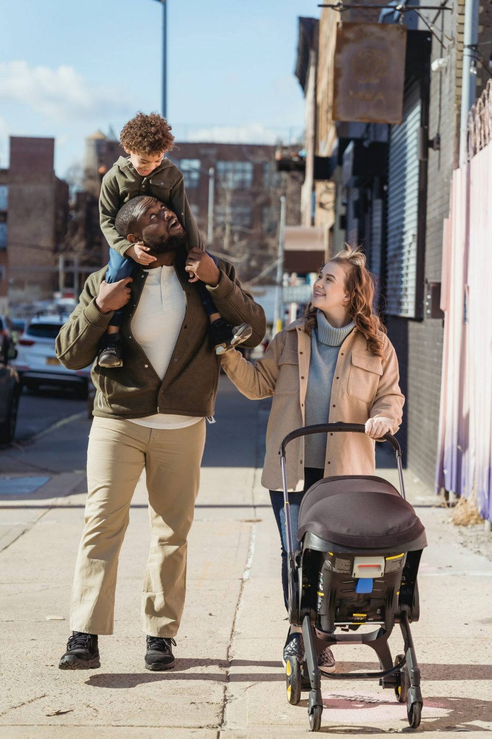 family taking a walk with baby and the stroller through a city street