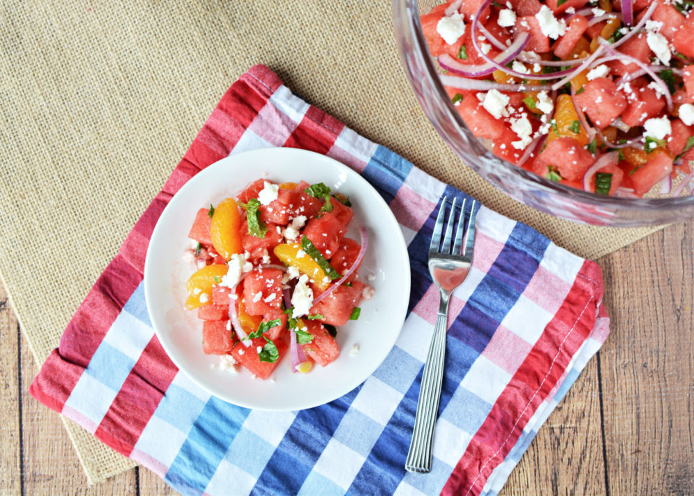  A bowl of watermelon, mandarin, and mint salad with onions and feta.
