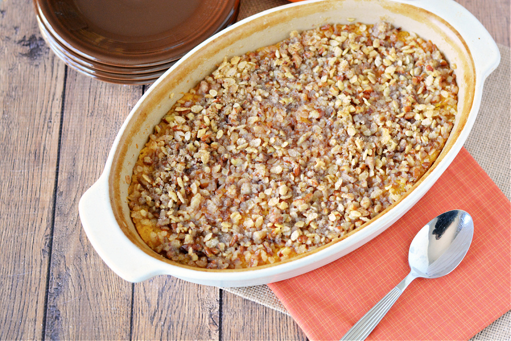 casserole dish filled with butternut squash topped with chopped pecans