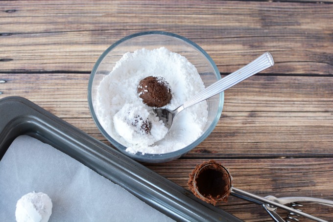 cookie dough ball in a bowl of powdered sugar