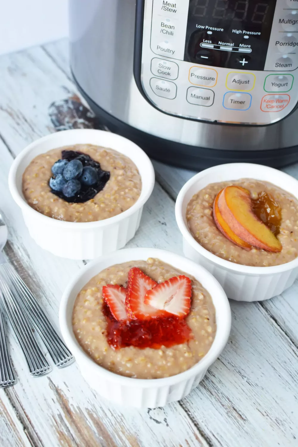 Oatmeal in white bowls with fresh strawberries, blueberries and peaches