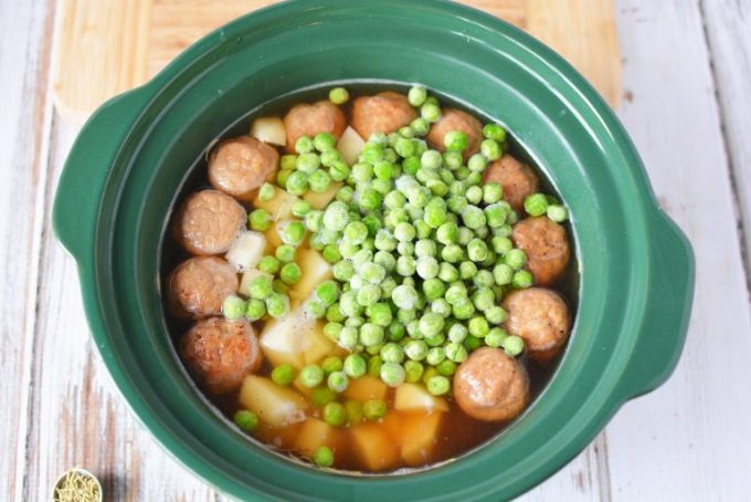 crock pot filled with meatballs and peas and potatoes