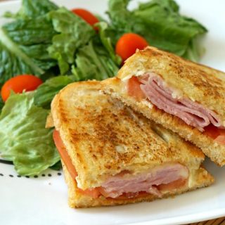 Grilled Ham and melted Brie Sandwich on a plate with a salad