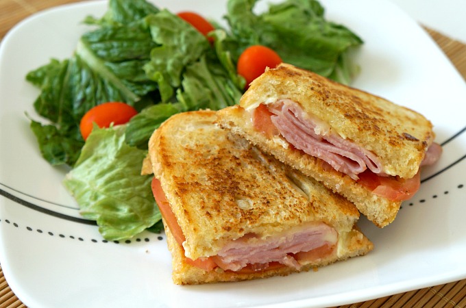 Grilled Ham and melted Brie Sandwich on a plate with a salad