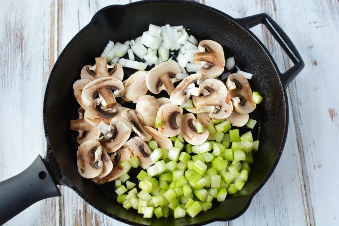 chopped onions and celery and sliced mushrooms in a cast iron skillet