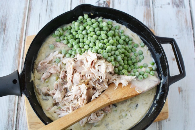 shredded turkey and frozen peas in a cast iron skillet on top of sauce