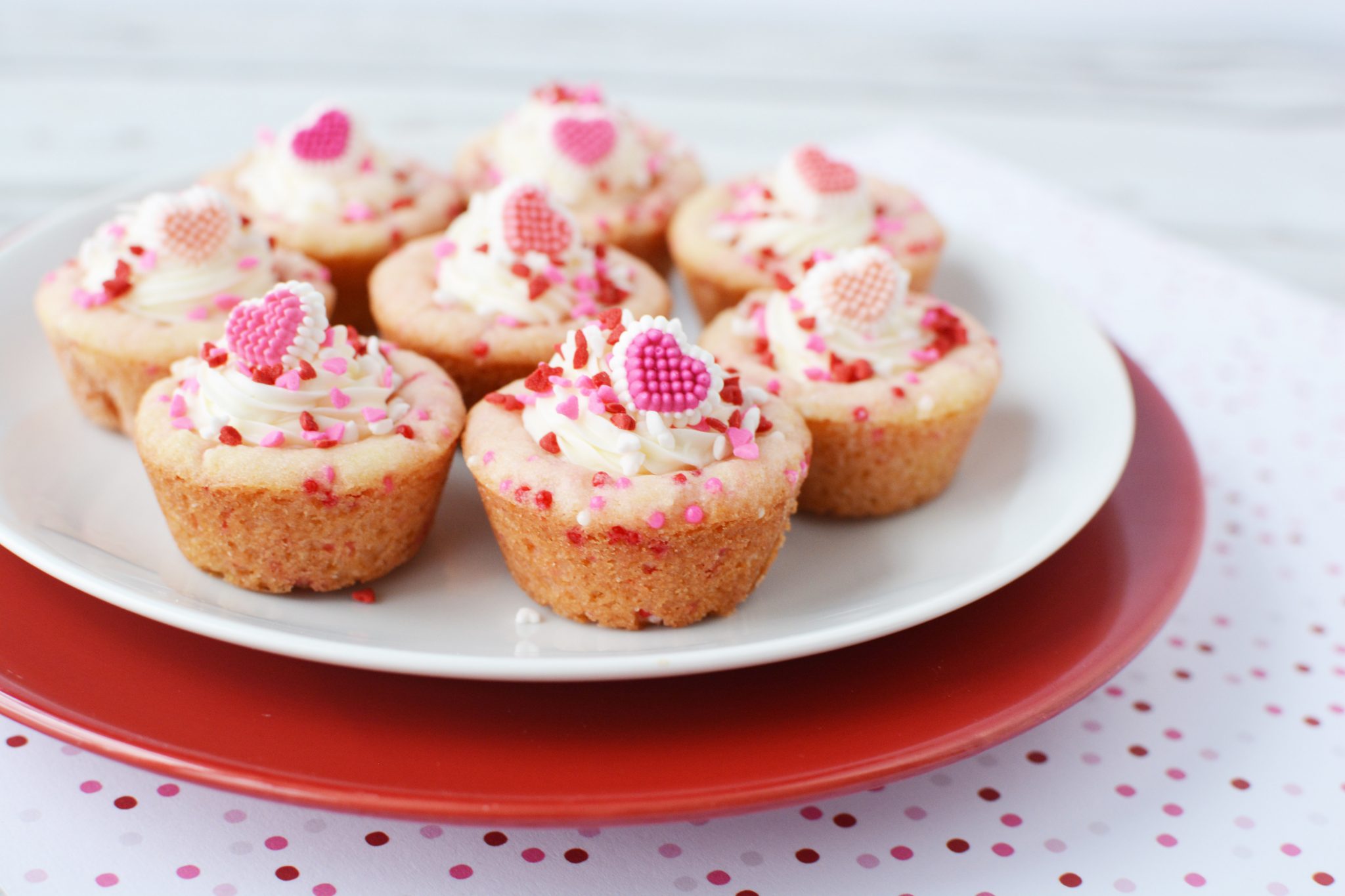 Sugar Cookie Cups filled with frosting and covered with red and pink sprinkles sitting on stainless steel cooling racks