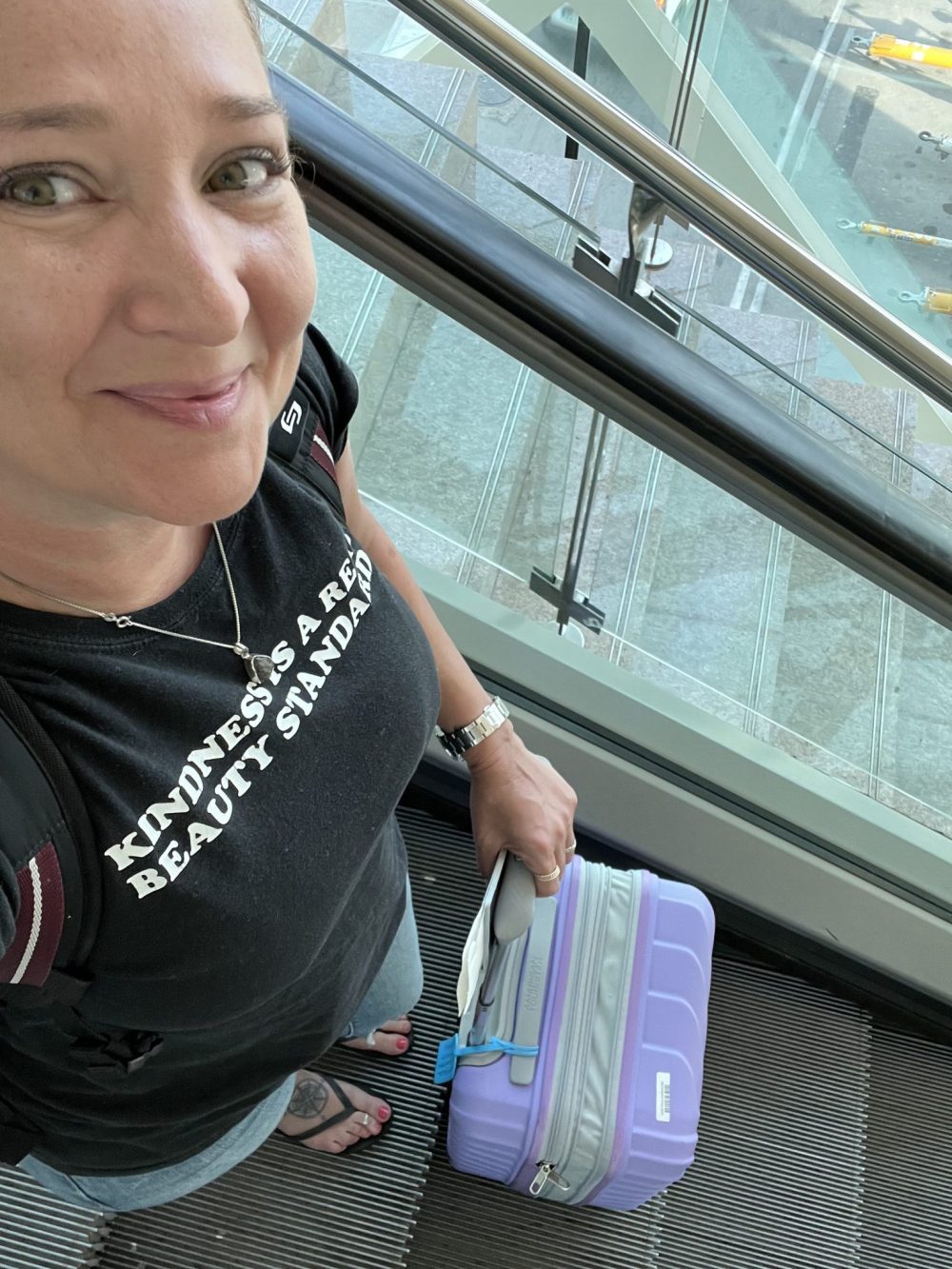 Jennifer with a carry on suitcase on an airport escalator