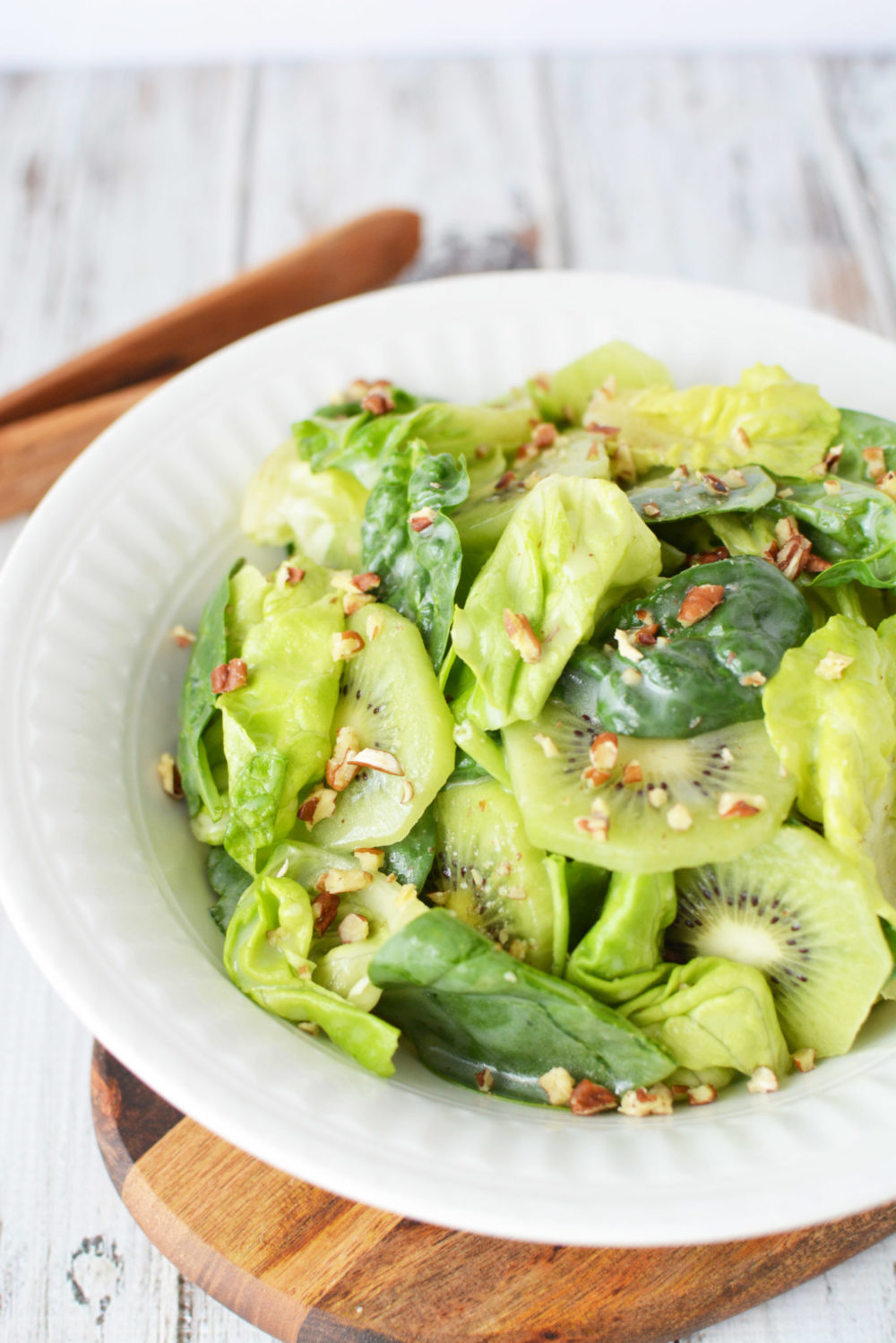 butter lettuce, spinach, and fruit in a bowl with pecans on top