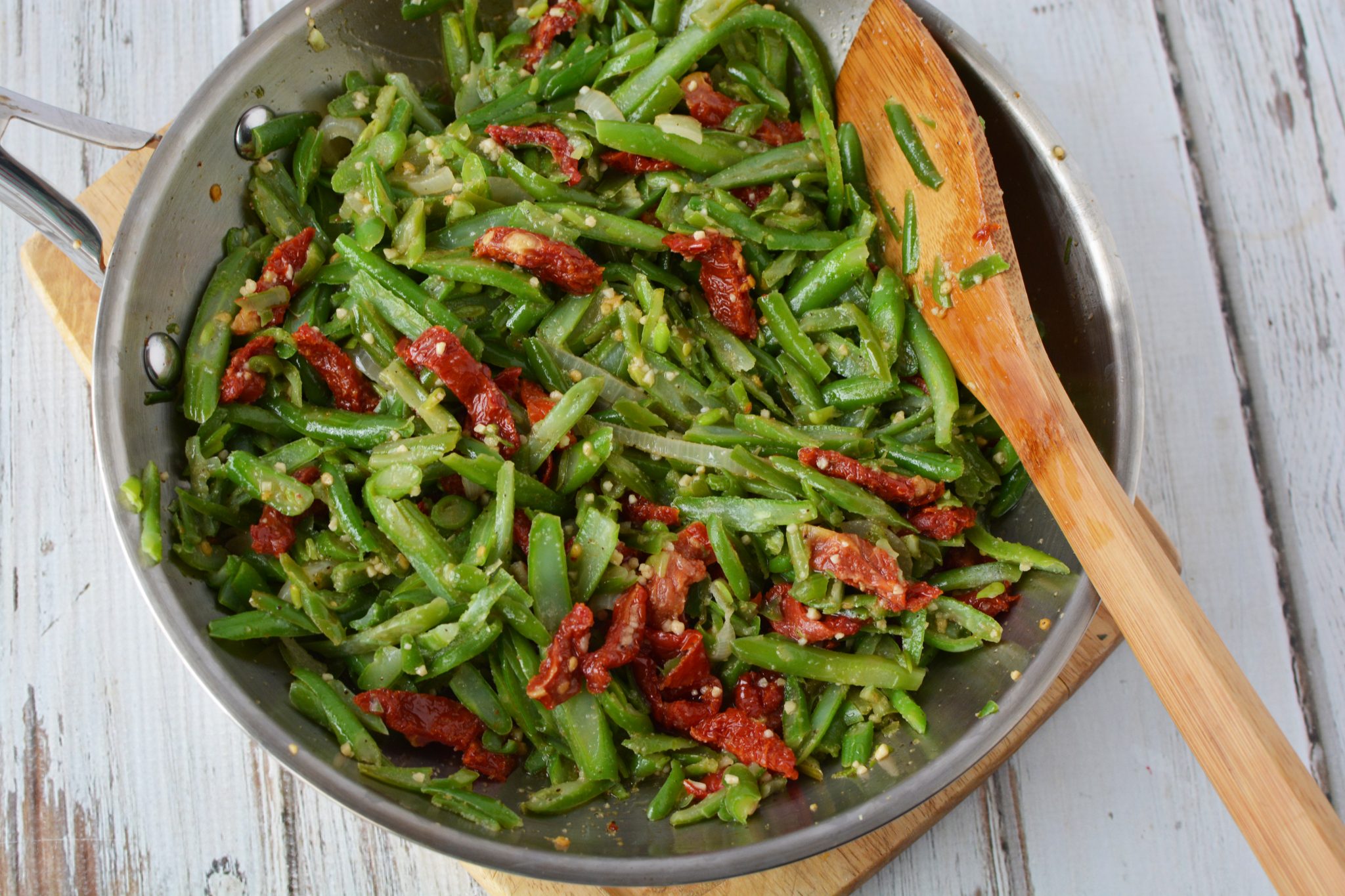 green beans, garlic, onions and tomatoes in a frying pan