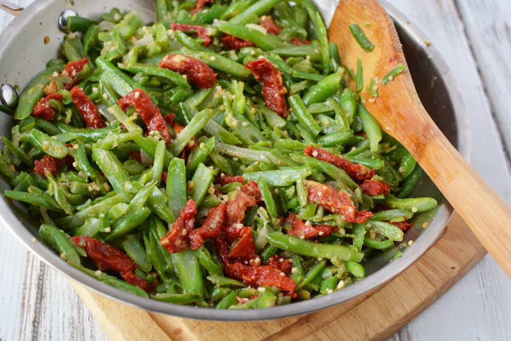 a bowl full of string beans and julienne tomatoes