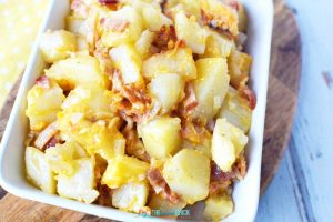 chunks of potatoes with bacon and cheese in a white dish