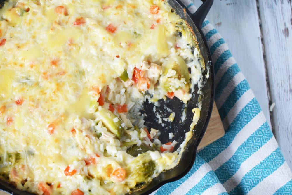 overhead shot of a cast iron skillet filled with rice, chicken, veggies and brussels sprouts in a creamy sauce