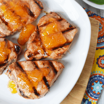 Grilled Pork Chops with peaches on top on a plate