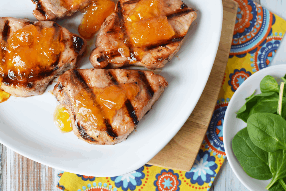 Grilled Pork Chops with peaches on top on a plate