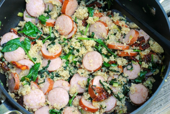 skillet filled with spinach, quinoa, garlic and sausage