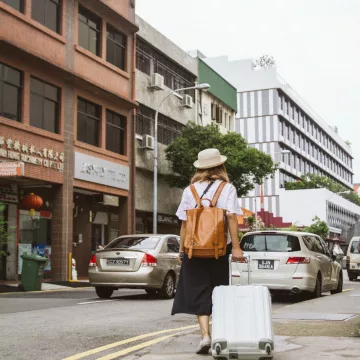 woman rolling a suitcase down the street