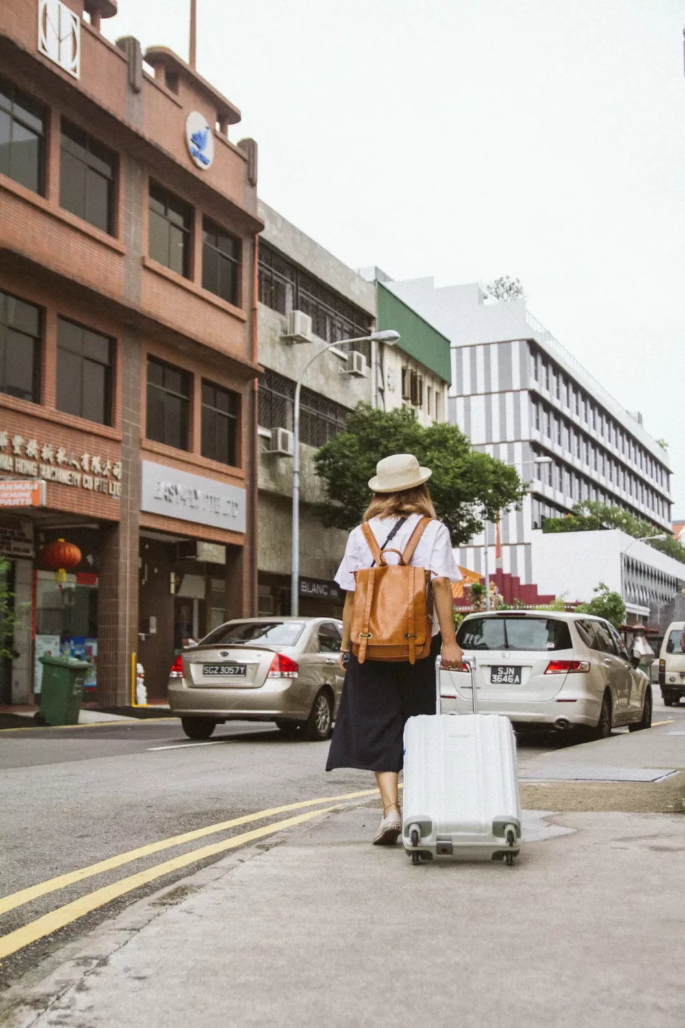 woman rolling a suitcase down the street
