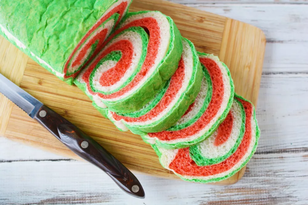 loaf of red white and green bread sliced into pieces on a wooden cutting board