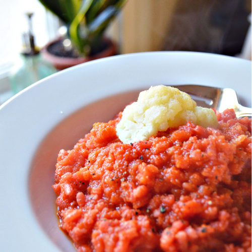 risotto colored with beets and carrots and topped with a piece of white cauliflower