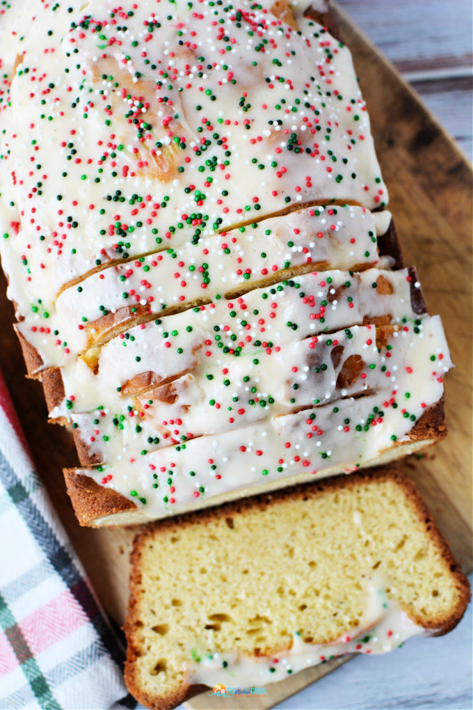 Eggnog Bread covered in white icing with Christmas themed sprinkles