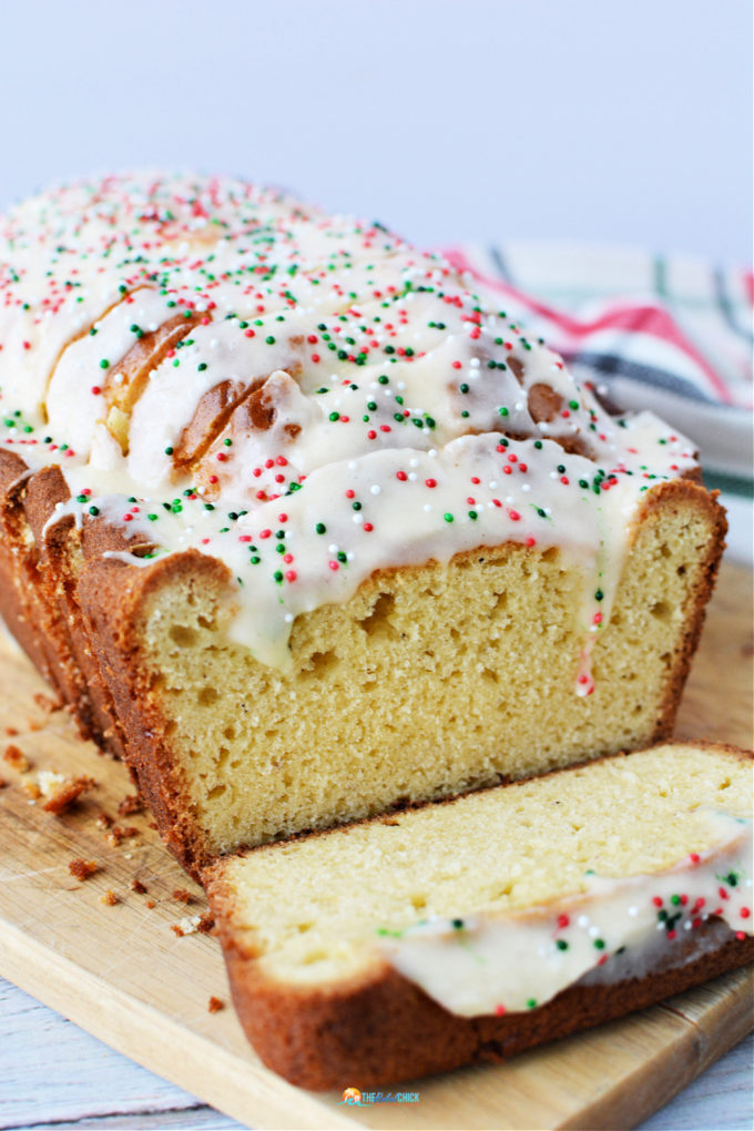 Eggnog Bread covered in white icing with Christmas themed sprinkles