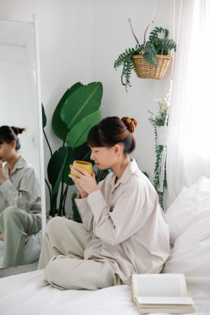 woman enjoying a cup of tea in bed with a book