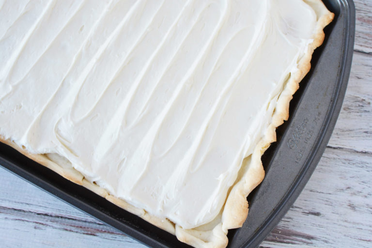cheesecake mixture spread over pie crust in a baking pan