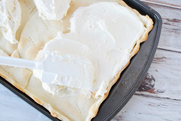 cheesecake mixture spread over pie crust in a baking pan