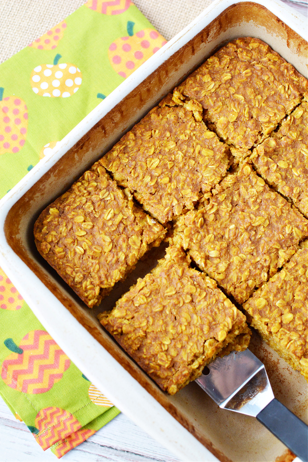 overhead shot of square of baked oatmeal filled with pumpkin and spices in a baking dish