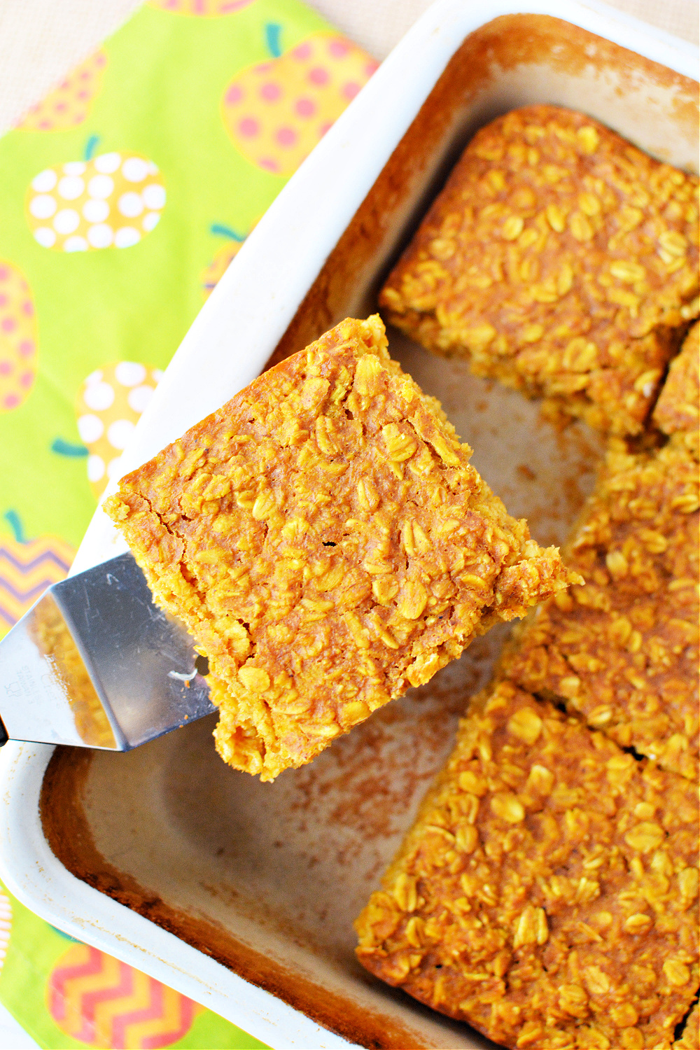overhead shot of square of baked oatmeal filled with pumpkin and spices in a baking dish