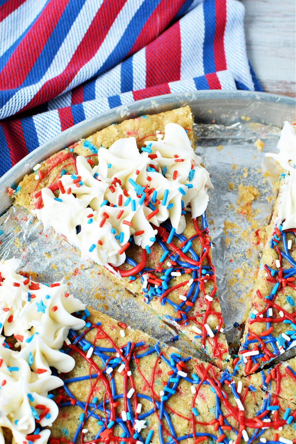 A slice of cookie pizza decorated with red, white, and blue frosting 