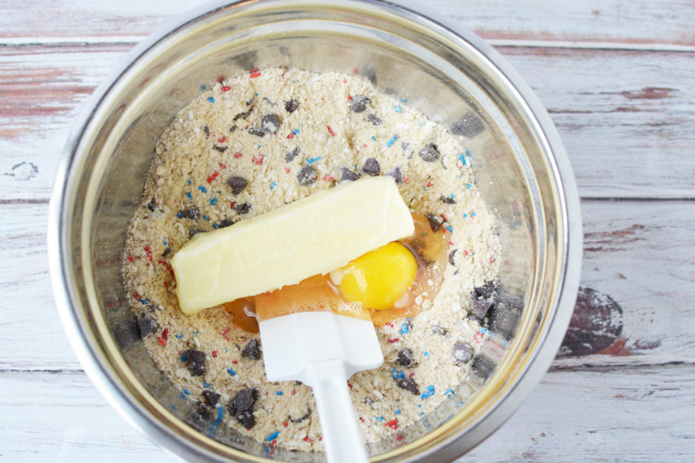 Adding butter and egg to the dry cookie dough ingredients 