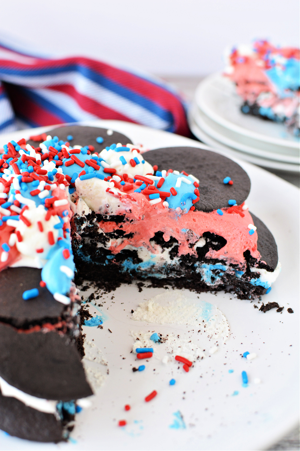 A red, white, and blue icebox cake with chocolate wafers, with a slice cut out of it