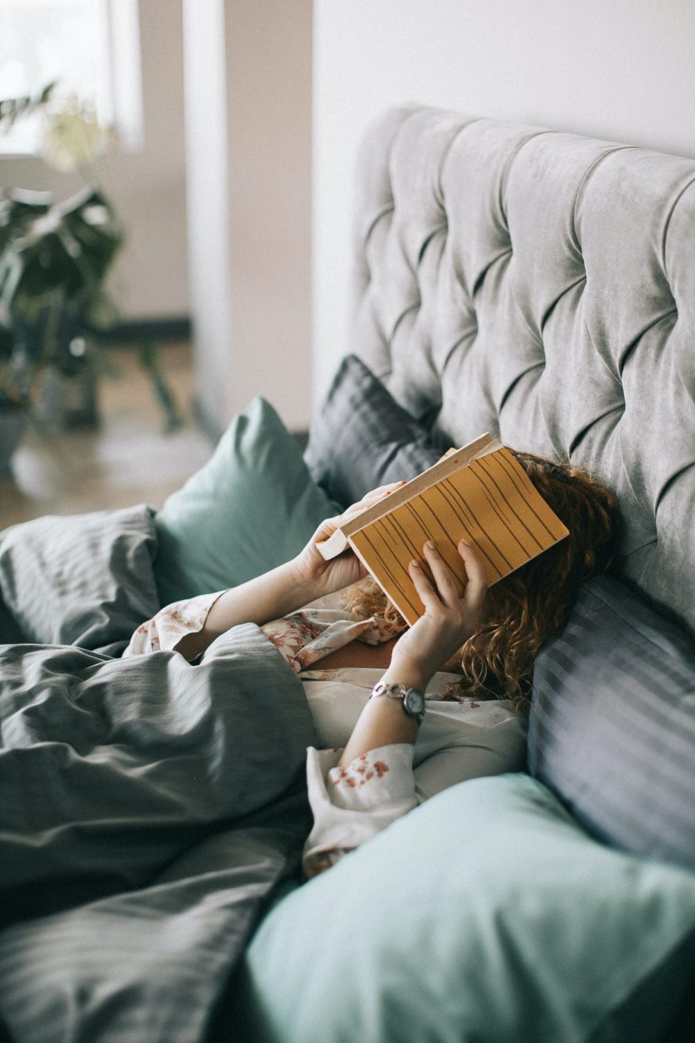 Woman in bed alone reading a book and relaxing