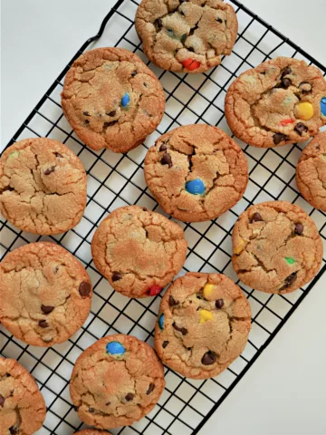 golden brown cookies with chocolate chips and M&Ms candies on a wire cooling rack