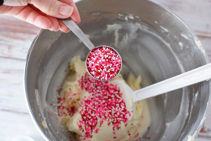 pouring red and pink sprinkles into cake batter