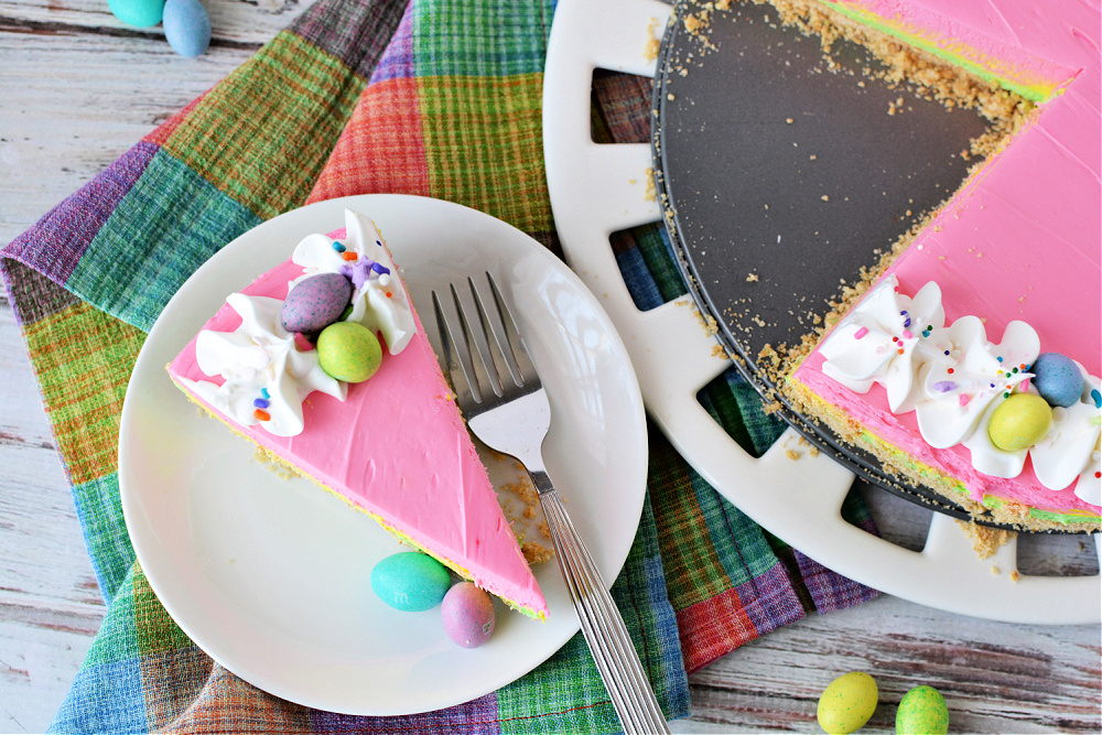 colorful dessert with pink, yellow and green filling, a graham cracker crust and whipped cream on top with easter candies