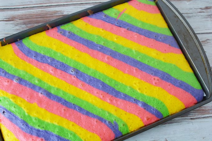 pink, purple, yellow and green cake batter in a baking pan